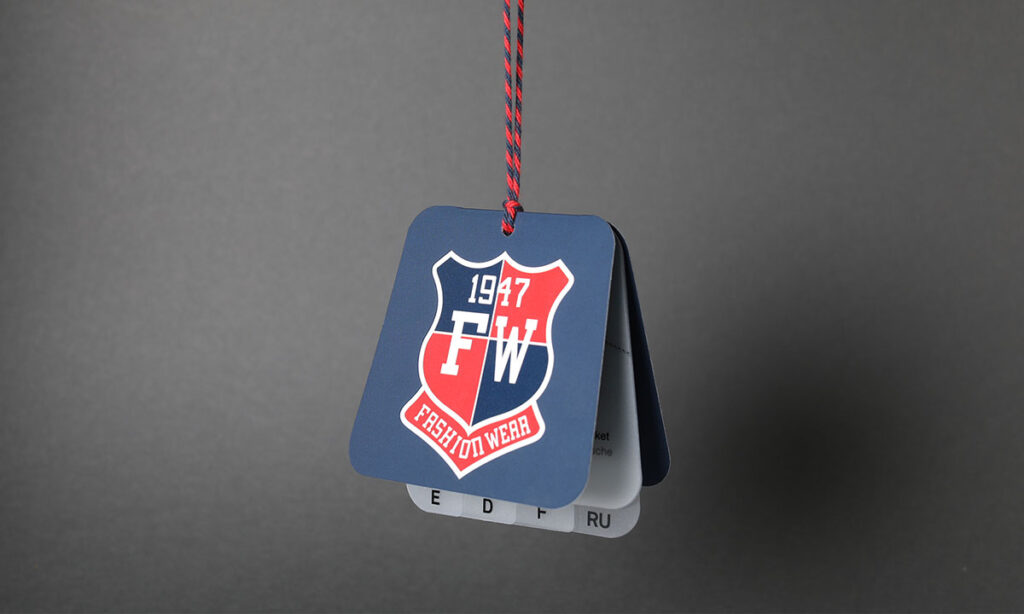 Blaues Hangtag, mit mehreren Einlegern in verschiedenen Sprachen, mit College-Wappen-Design an einem dunkelblauen Sakko auf weißem Kleiderbügel – Hangtags im Einsatz am Point of Sale von WEROCA Kartonagen Bielefeld