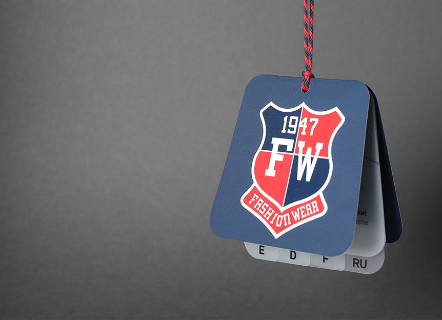 Blaues Hangtag, mit mehreren Einlegern in verschiedenen Sprachen, mit College-Wappen-Design an einem dunkelblauen Sakko auf weißem Kleiderbügel – Hangtags im Einsatz am Point of Sale von WEROCA Kartonagen Bielefeld