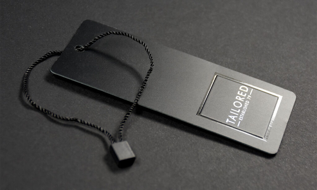 Zweiteiliges schwarzes mattes Hangtag mit partiellem Glanzlack, weißem Druck und schwarzem Plombenfaden mit – hochwertige Hangtag-Sonderlösungen von WEROCA Kartonagen Bielefeld