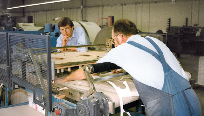 Zwei WEROCA-Mitarbeiter an der ersten Flachbettstanze im Jahr 1992 – Meilenstein in der Produktionsentwicklung der WEROCA Kartonagen GmbH & Co. KG in Bielefeld