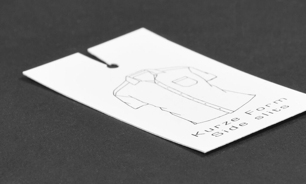 Weißes Hemd-Trimming mit Knopfloch, Figurskizze und zweisprachiger Schnittangabe „Kurze Form / Side Slits" – informative Trimming-Lösungen für Hemden und Oberbekleidung von WEROCA Kartonagen Bielefeld