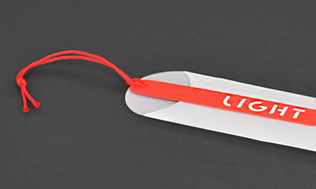 Weißes "Light"-Hangtag von WEROCA Kartonagen Bielefeld mit rotem Streifen und roter Kordel, Detailaufnahme für Fashion & Textil-Hangtags.