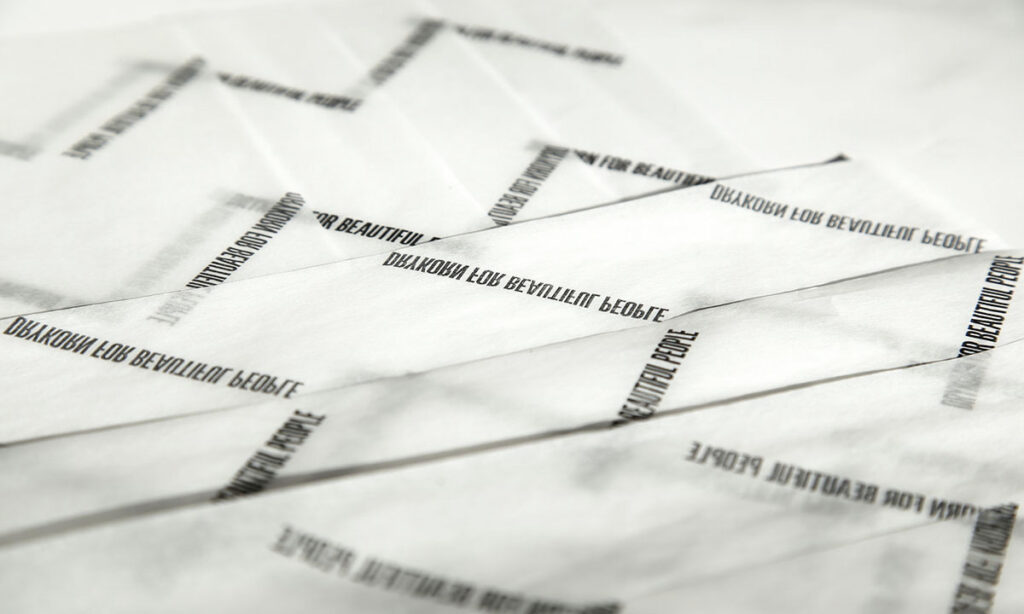 Bedrucktes Seidenpapier von WEROCA Kartonagen Bielefeld mit Schriftzug "Born for Beautiful People" in Falten gelegt, Detailaufnahme für Fashion & Textil-Verpackung.